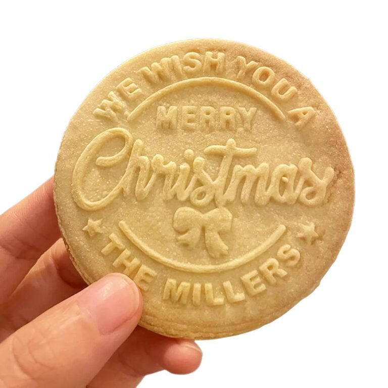 Hand holding a round Christmas cookie with embossed message "Merry Christmas, The Millers"