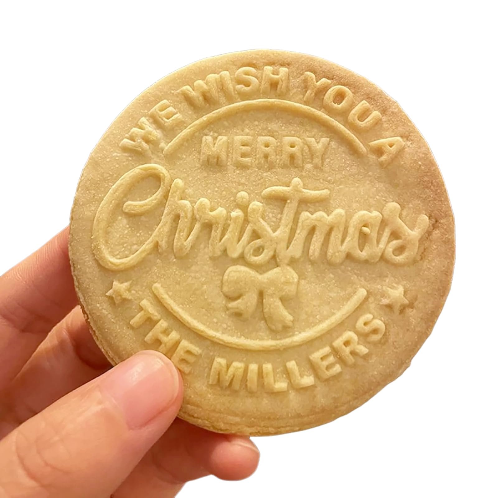 Hand holding a round Christmas cookie with embossed message "Merry Christmas, The Millers"