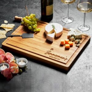 Wooden charcuterie board with cheese, grapes, wine, and candles