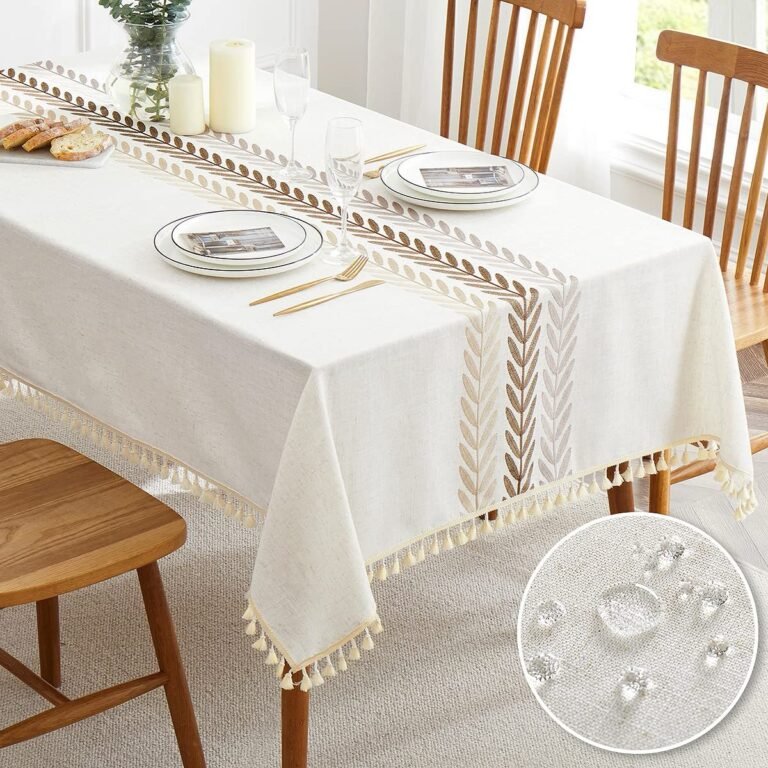 White tablecloth with leaf design, set table with plates, glasses, and chairs